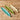 Three ceramic leaf-shaped dishes in teal, green, and beige on a wooden surface.