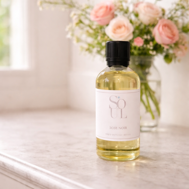 Bottle of oil labeled 'Soul' on a marble surface with flowers in the background